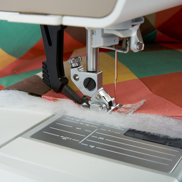 Close-up of a sewing machine needle working on fabric with a colorful background