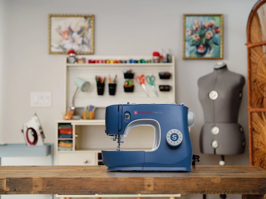 Singer M3335 blue sewing machine in a home sewing workspace